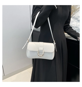 Close-up of a white leather underarm bag featuring a golden horseshoe metal buckle detail