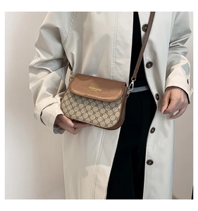 Detail of vintage brown monogram canvas saddle bag with gold lettering and leather strap