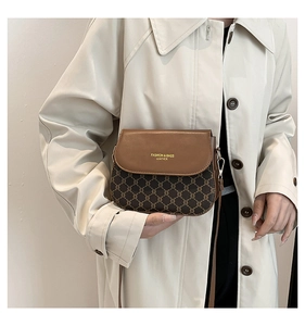 Close-up of brown vintage crossbody saddle bag with fashion logo and golden hardware