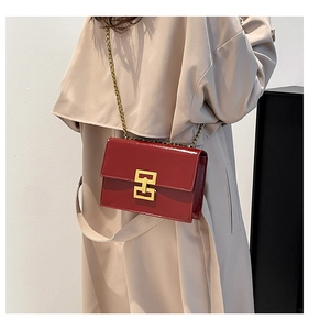 Detailed macro view of vintage red glossy leather bag with golden metallic square lock