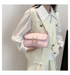 Close-up of light pink leather crossbody bag featuring a U-shaped gold metallic buckle