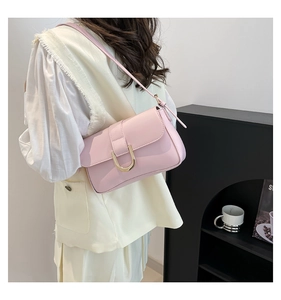 Pink glossy leather shoulder bag with golden horseshoe buckle detail shown on model