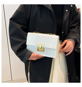 Close-up of white leather crossbody bag featuring gold metal chain and rectangular lock