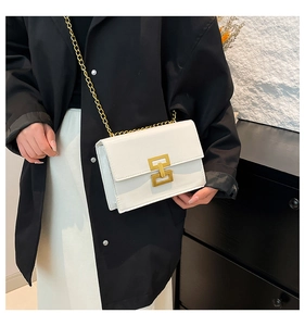 Close-up of white leather square bag with gold H-buckle and metal chain strap detail