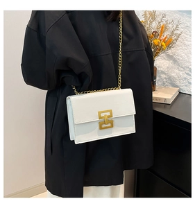 Detail of white glossy leather shoulder bag with gold geometric buckle and chain strap