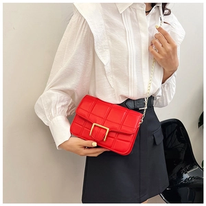 Close-up of red quilted leather handbag with gold metal clasp and chain strap detail