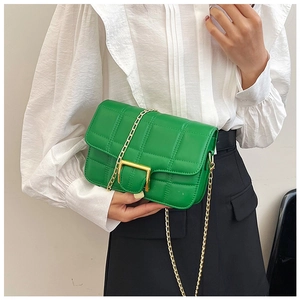 Close-up of bright green quilted shoulder bag with gold chain strap and metal buckle