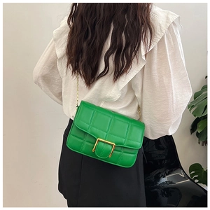 Detail of bright green quilted crossbody bag with gold square clasp and chain strap