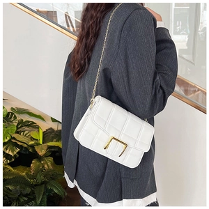 Detailed view of white quilted leather shoulder bag with gold hardware on a model