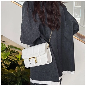 Detail view of a white checkered crossbody bag with gold chain and square buckle on a model