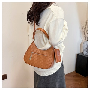 Detail der braunen gewebten Hobo-Tasche mit passender Geldbörse an einem Modell