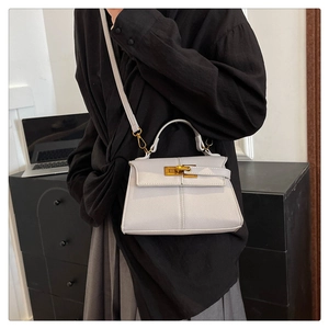 Modella con borsa a trapezio in pelle bianca e chiusura dorata per stile da ufficio