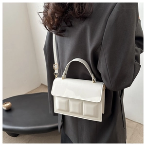 Detail of white PU leather crossbody bag with geometric design and gold hardware strap