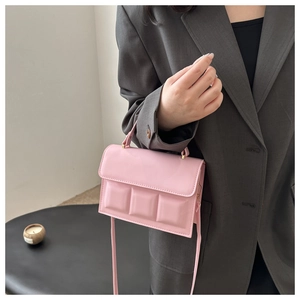 Pink chocolate block textured mini handbag with crossbody strap shown on model suit