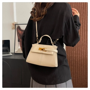 Dettaglio della borsa a mano trapezoidale color crema con chiusura girevole in metallo