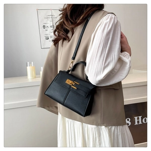 Elegante borsa a trapezio in pelle nera con chiusura dorata indossata da una modella