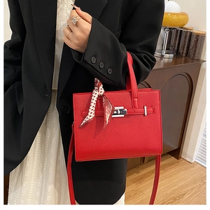 Détail du sac à main rouge en cuir grainé avec fermoir rotatif argenté et foulard en soie