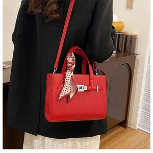 Détail du sac cabas rouge texture litchi avec fermoir argenté et poignée ornée d'un foulard