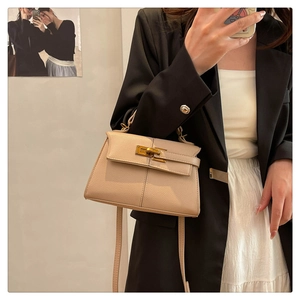 Dettaglio macro della borsa in pelle beige a grana con chiusura girevole dorata e finiture