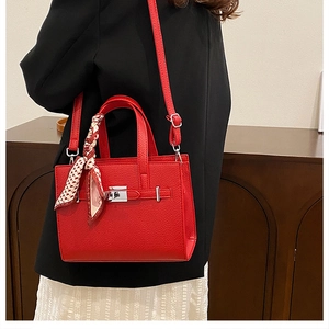 Détail du sac cabas en cuir grainé rouge avec boucle argentée et foulard en soie décoratif