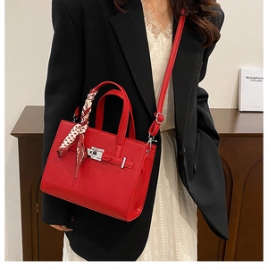 Gros plan du sac en cuir litchi rouge avec fermoir argenté et foulard imprimé déco
