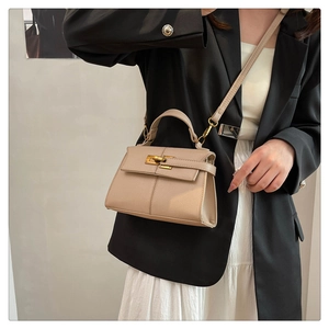 Dettaglio della borsa beige in pelle martellata con chiusura in metallo dorato su modella