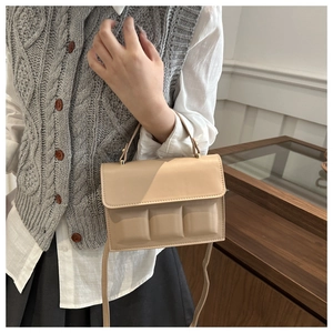 Detail of beige puffy crossbody bag with chocolate block texture on model