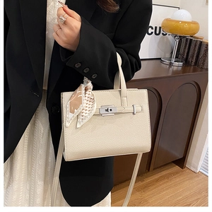 Détail du sac Kelly en cuir grainé crème avec foulard en soie et fermoir argenté brillant