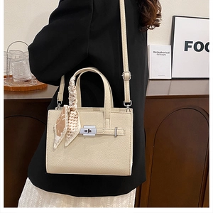 Détail d'un sac cabas beige texture litchi avec fermoir pivotant et foulard en soie