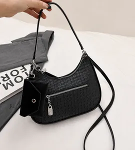 Close-up of woven shoulder bag in black with silver zipper and mini coin purse charm