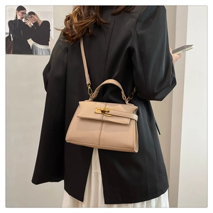 Vista dettagliata di una borsa a mano trapezoidale beige con trama in pelle e tracolla