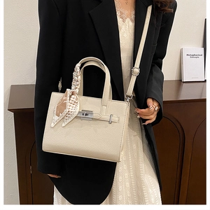 Détail du sac crème en cuir grainé avec fermoir argenté et foulard en soie décoratif
