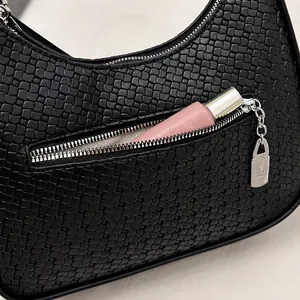 Detail of the woven black shoulder bag featuring a silver zipper and a metal lock charm