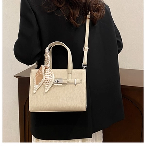 Détail du sac à main beige en cuir grainé avec fermoir argenté et poignée en foulard