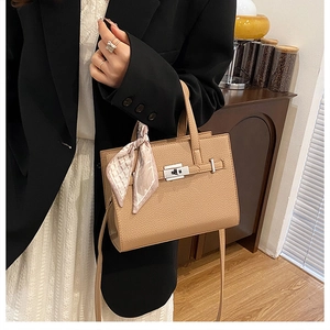 Détail d'un sac à main en cuir marron clair avec foulard en soie et finitions argentées