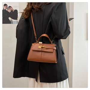 Dettaglio di borsa a mano trapezoidale in pelle marrone con texture a grana litchi