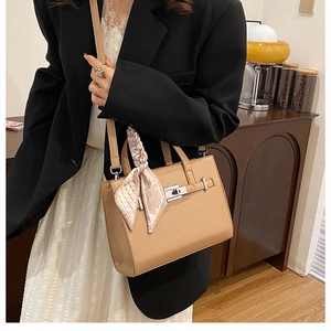 Détail du sac cabas en cuir à motif litchi avec fermoir rotatif et foulard en soie décoratif