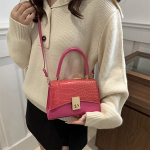 Pink crocodile-embossed crossbody bag with gold twist lock shown on a female model
