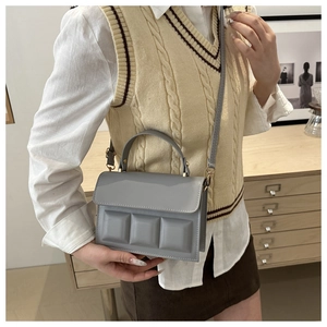 Detailed side view of grey textured mini square bag with three 3D blocks on the flap