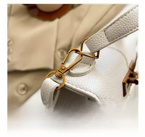 Dettaglio della pelle martellata bianca con fibbie in ottone vintage e chiusura a scatto