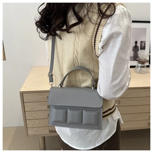 Detail of dark grey chocolate block handbag with adjustable strap and top handle