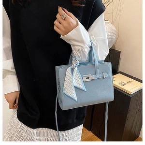 Gros plan du sac à main bleu clair avec motif litchi, foulard en soie et fermoir métal