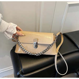 Détail du sac beige en cuir verni plissé avec chaîne argentée et fermoir en métal
