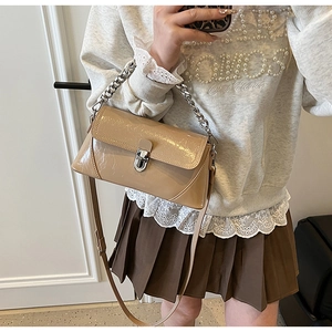 Selfie miroir montrant un sac baguette en cuir verni marron clair avec chaîne argentée