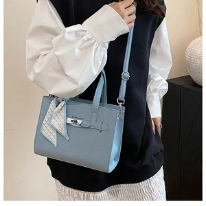 Détail d'un sac cabas bleu clair à motif litchi avec fermoir tournant en argent et foulard