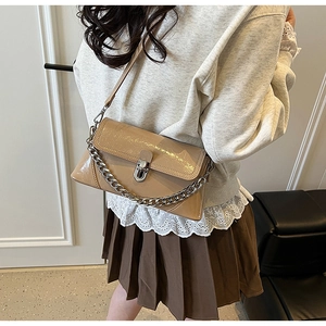 Détail de sac bandoulière en cuir verni kaki avec chaîne argentée et fermoir métal