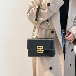 Retro black leather chain shoulder bag with gold geometric lock worn by a model