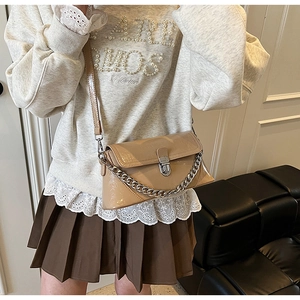Détail du sac bandoulière en cuir verni beige avec chaîne argentée et boucle en métal