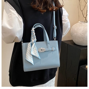 Détail du sac cabas bleu clair avec motif litchi, fermoir argenté et foulard