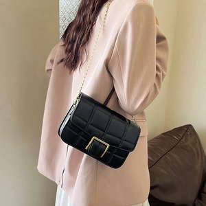 Classic black quilted crossbody bag with gold chain strap shown on model in pink blazer
